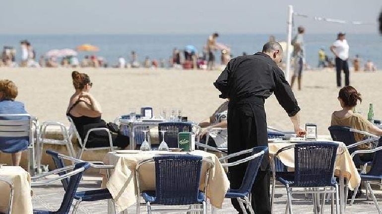 Imagen de un camarero en un restaurante frente al mar.