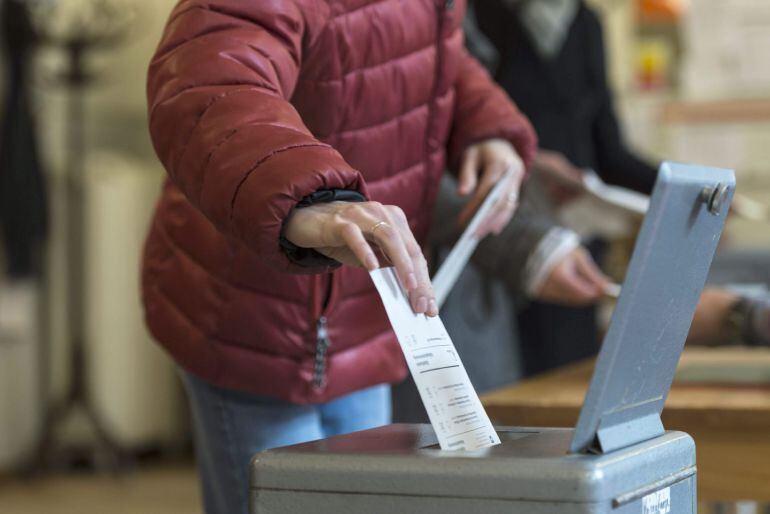 Una votante suiza emite su voto durante un referéndum en un colegio electoral en Berna.