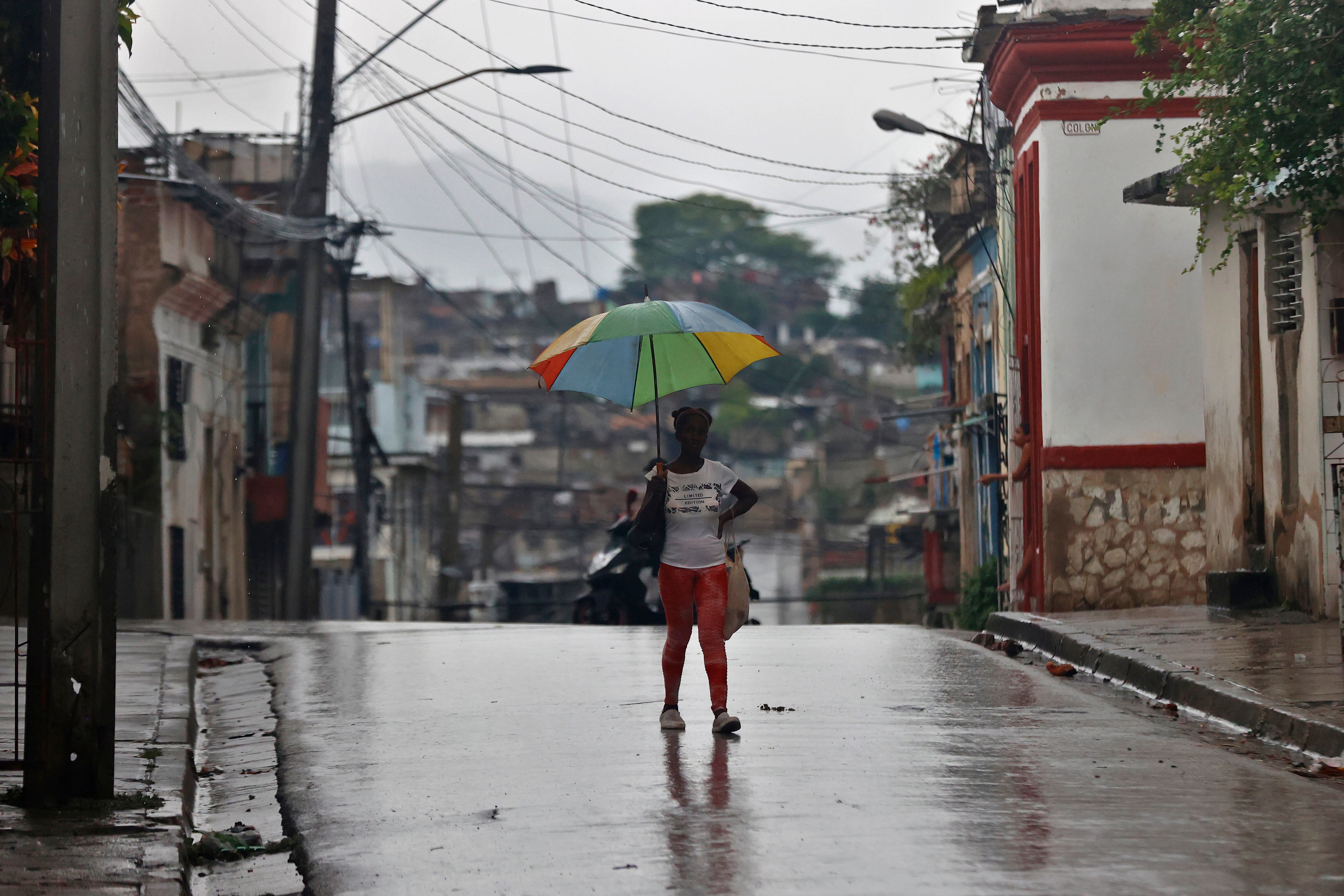 Una persona se protege de la lluvia en Santiago de Cuba.