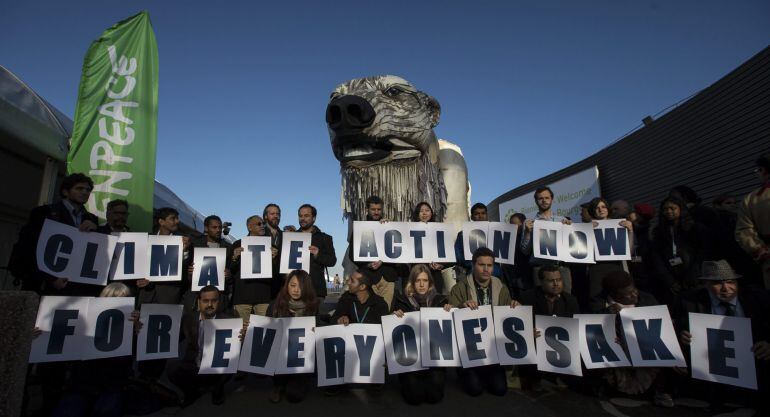  Un grupo de representantes de Greenpeace muestran una pancarta en la que se lee &quot;Acción por el clima ahora para el bien de todos&quot; delante de una réplica de un oso polar gigante