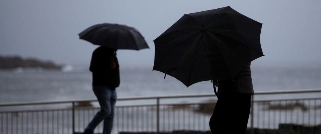 Dos personas caminaba hoy por el paseo marítimo