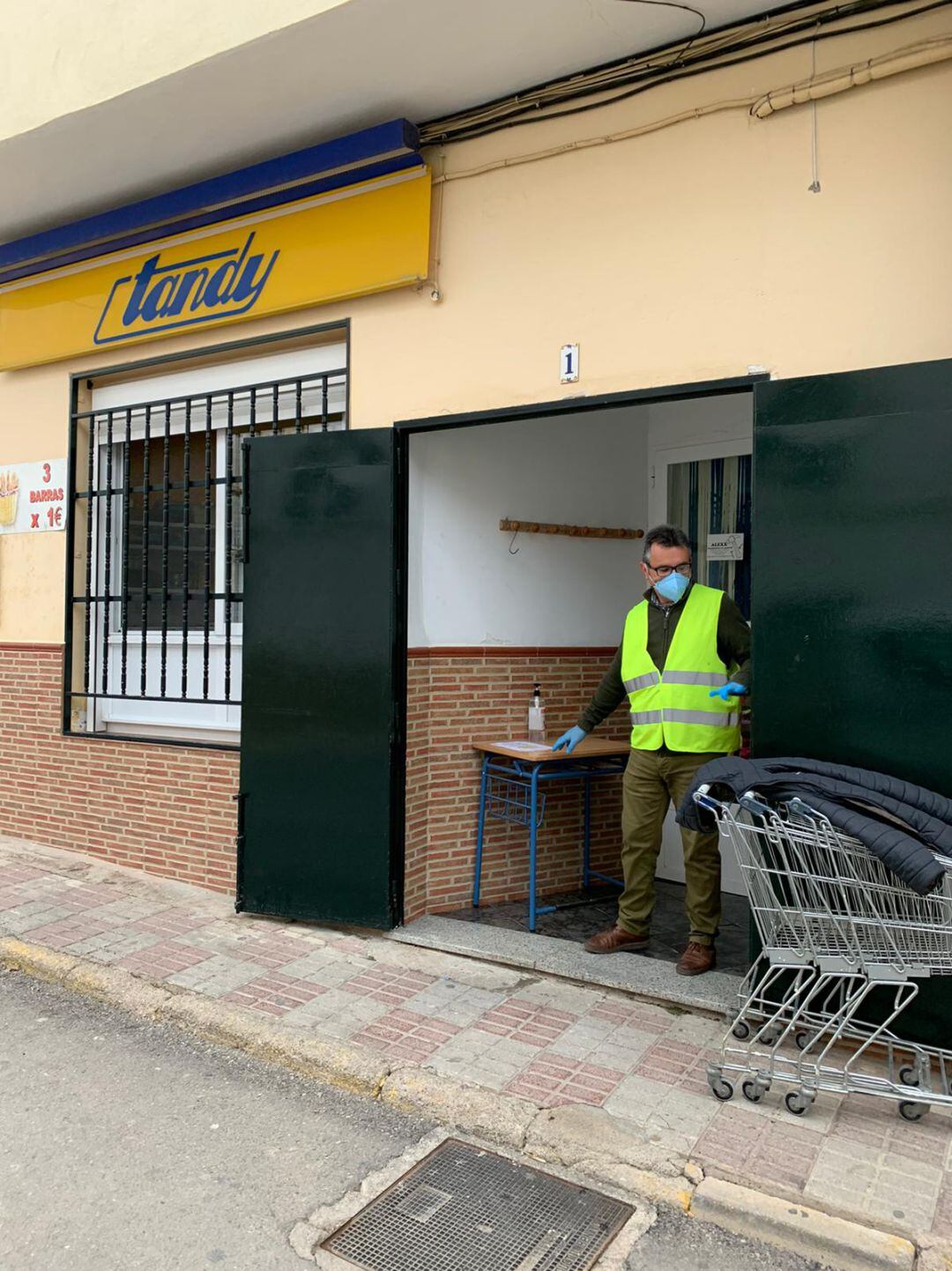 Voluntarios hacen que los vecinos se desinfecten las manos con gel hidroalcoholico a la entrada de los comercios