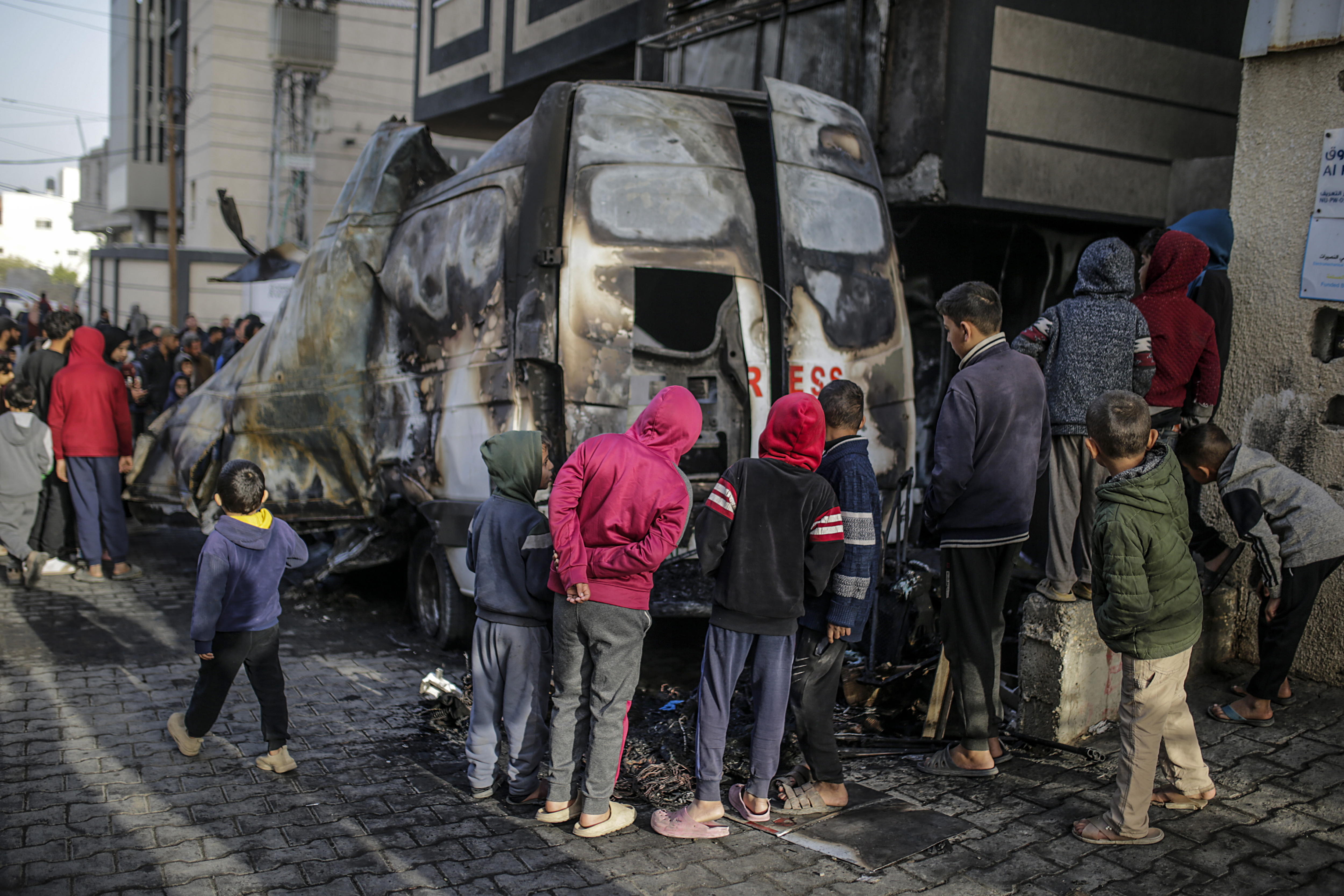 Palestinos inspeccionan un vehículo de prensa destruido cerca del hospital de Al Awda, después de un ataque aéreo israelí en el campamento de refugiados de Al Nuseirat, en la Franja de Gaza.