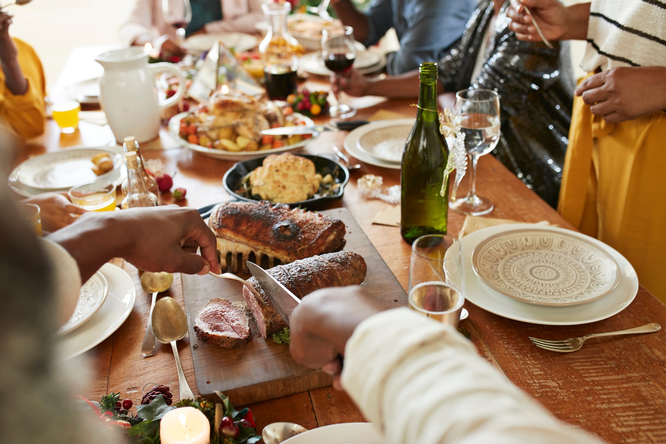 Cropped hands of mid adult man cutting meat in slices on dining table at home