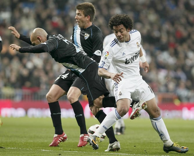 El defensa brasileño del Real Madrid, Marcelo Vieira (d), lucha por el balón con el defensa Manuel Gaspar, del Málaga CF, durante el partido, correspondiente a la vigésimo sexta jornada de Liga de Primera División, que ambos equipos disputan esta noche en