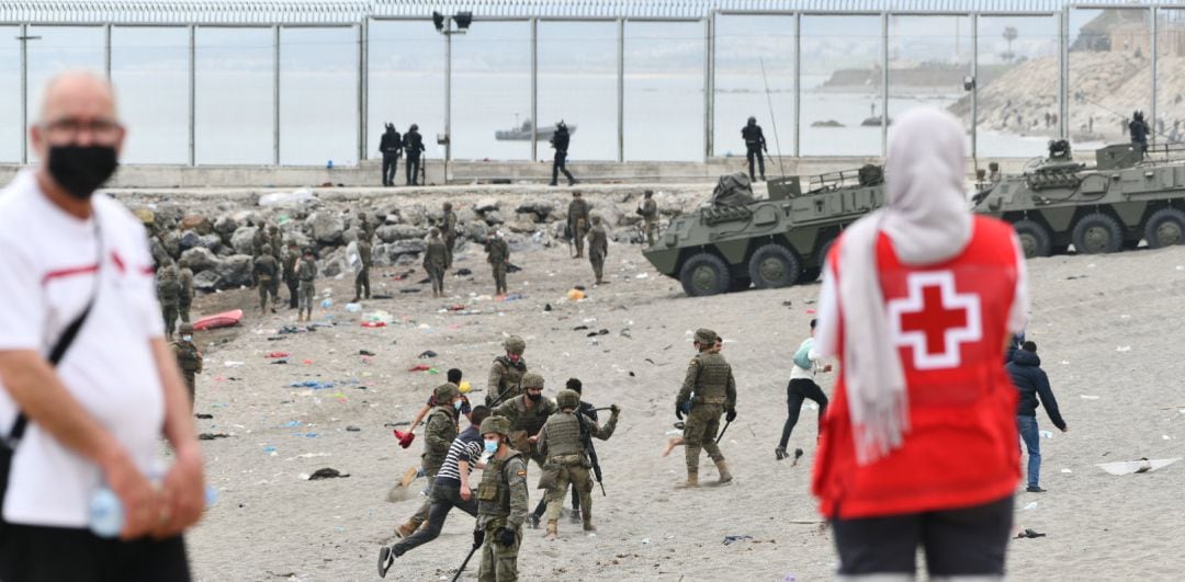 Una trabajadora de la Cruz Roja observa a los militares del ejército en una jornada marcada por las devoluciones en caliente que están efectuando a los migrantes que han entrado en Ceuta procedente de Marruecos, a 18 de mayo de 2021, en Ceuta, (España)