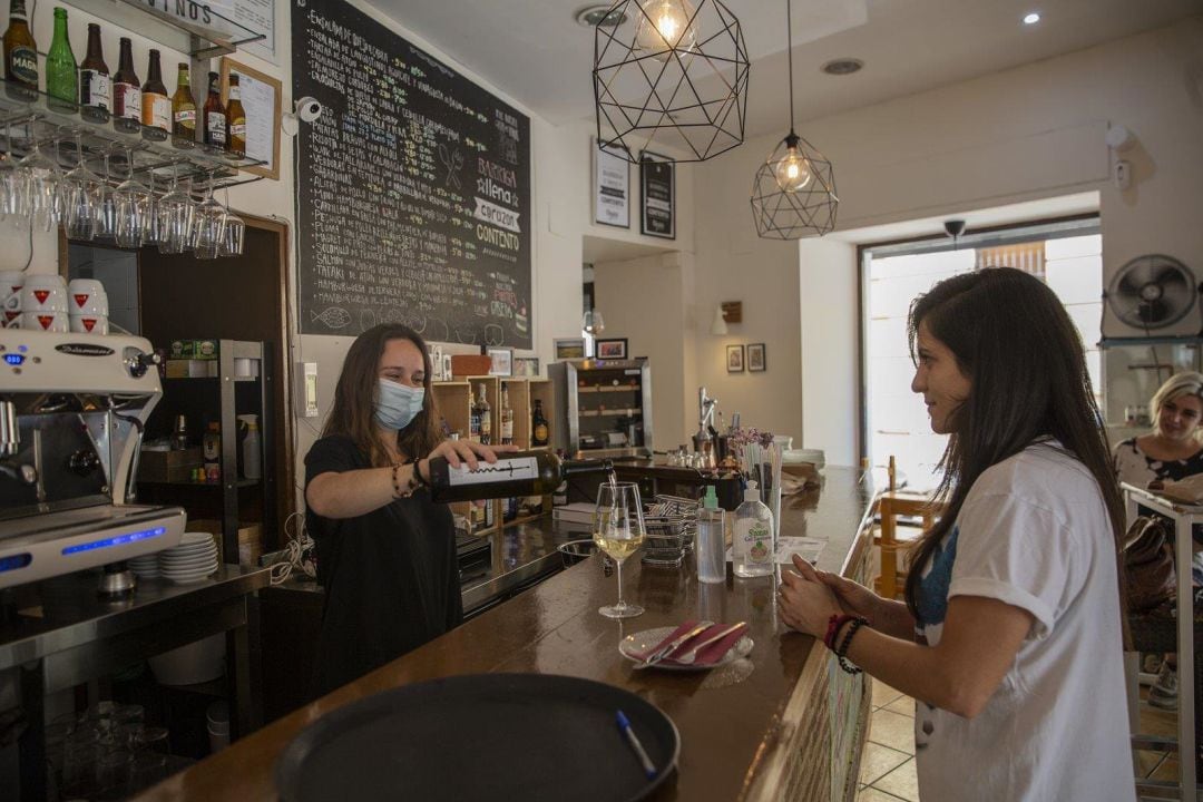 Una camarera sirve una copa de vino a una clienta