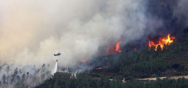 GRA298. EL PAYO (SALAMANCA), 06/08/2015.- Un helicóptero realiza una descarga sobre el incendio forestal declarado hoy en Acebo (Cáceres) que se encuentra a menos de un kilómetro de la localidad salmantina de Payo. Un albergue y varias casas aisladas han 