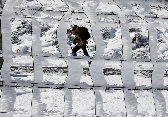Una persona pasea por el alto de Ibañeta donde la nieve caida durante esta madrugada ha vuelto a cubrir los montes del norte de la comunidad foral.