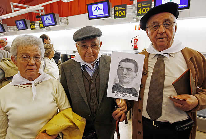 Familiares de un mártir posan con su fotografía mientras esperan el avión hacia Roma en el Aeropuerto de Madrid