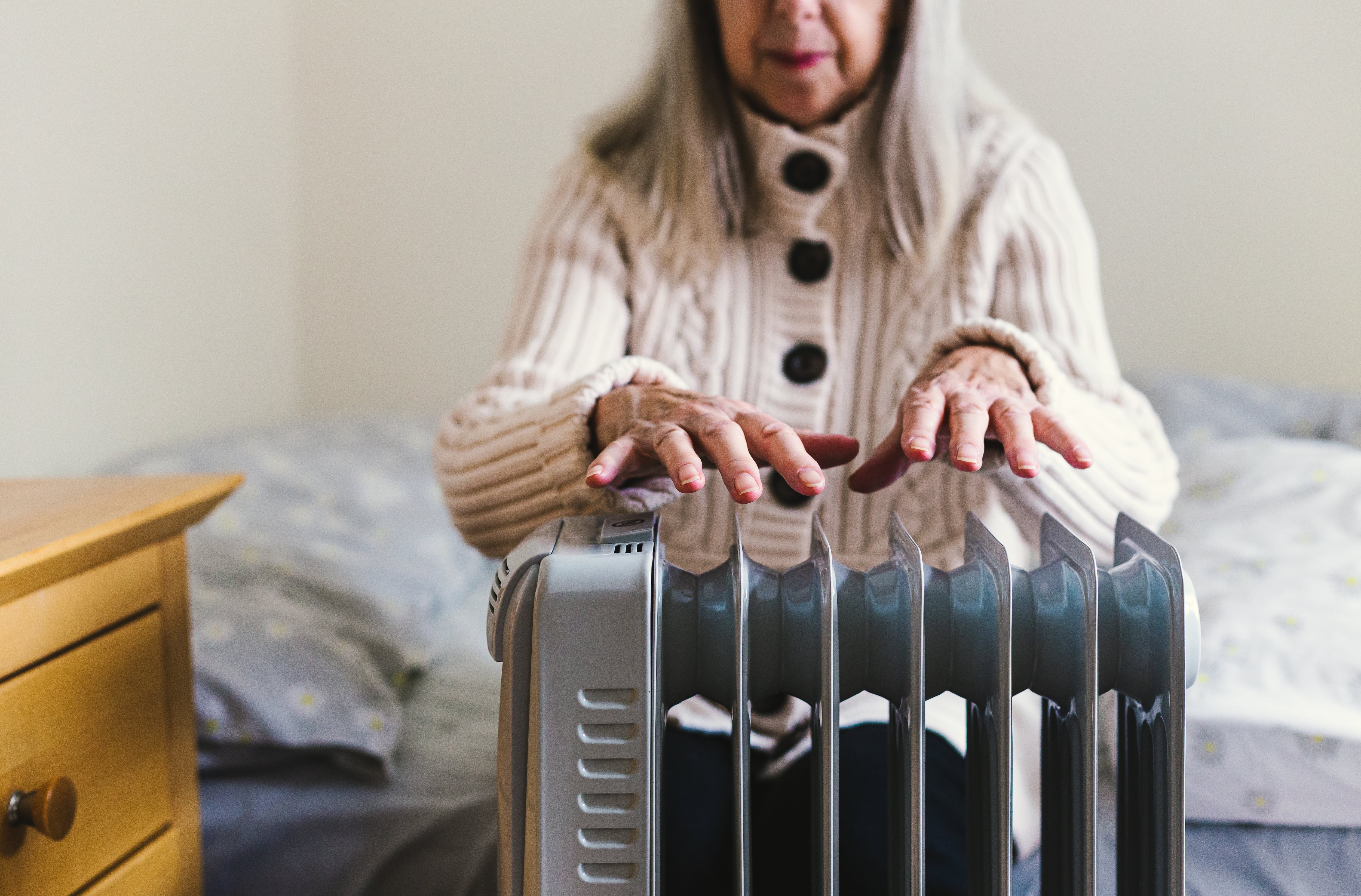 Imagen de archivo de una mujer calentándose con un radiador