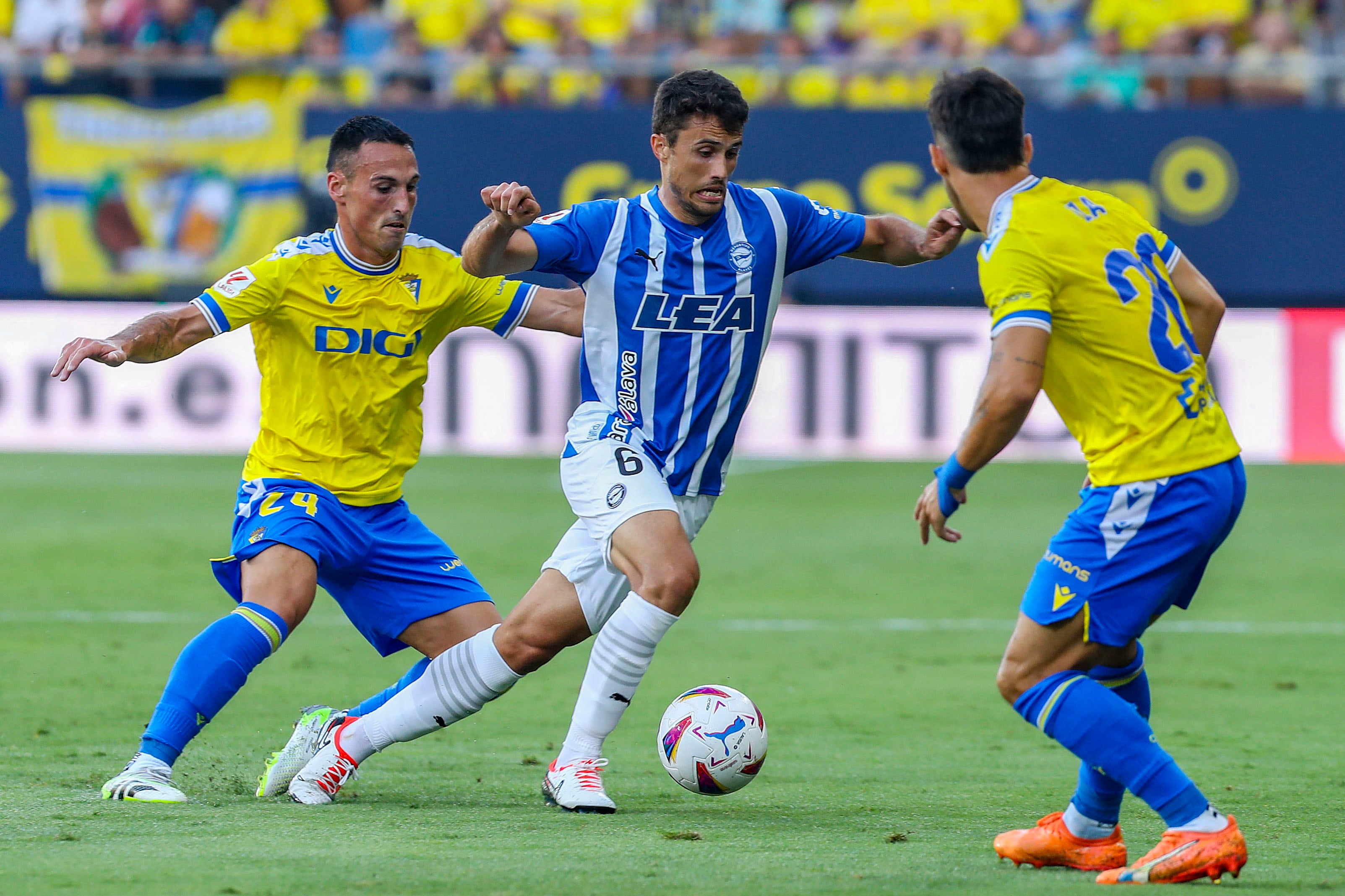 El jugador del Deportivo Alavés Ander Guevara (c) lucha por el balón con el centrocampista del Cádiz CF Fede San Emeterio y el defensa del Cádiz CF Iza Carcelén (d) durante el partido de Liga que enfrenta al Cádiz CF y al Deportivo Alavés en el estadio Nuevo Mirandilla.