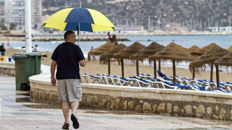 Un hombre con paraguas pasea por las playas valencianas