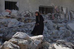 A woman makes her way through the rubble of damaged buildings after airstrikes by pro-Syrian government forces in the rebel held town of Dael, in Deraa Governorate, Syria February 12, 2016. REUTERS/Alaa Al-Faqir