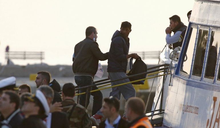 Un agente de Frontex lleva a un inmigrante a un barco turco en la isla griega de Lesbos para ser devuelto a Turquía. GIORGOS MOUTAFIS (REUTERS)