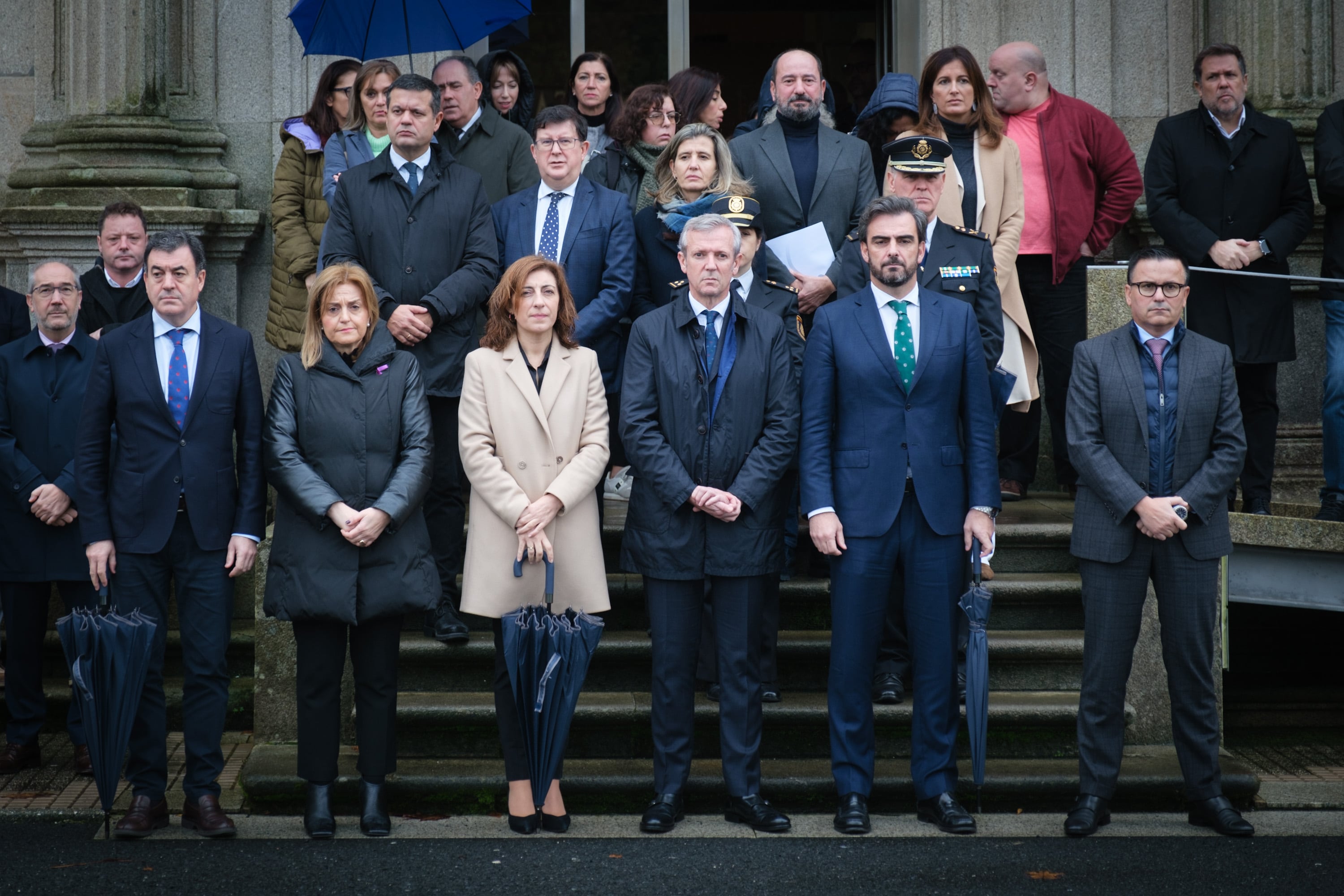 El presidente de la Xunta de Galicia, Alfonso Rueda, en el centro, flanqueado por sus dos vicepresidentes y parte de su equipo de gobierno, en el minuto de silencio en memoria de la mujer asesinada en Oroso a manos de su marido