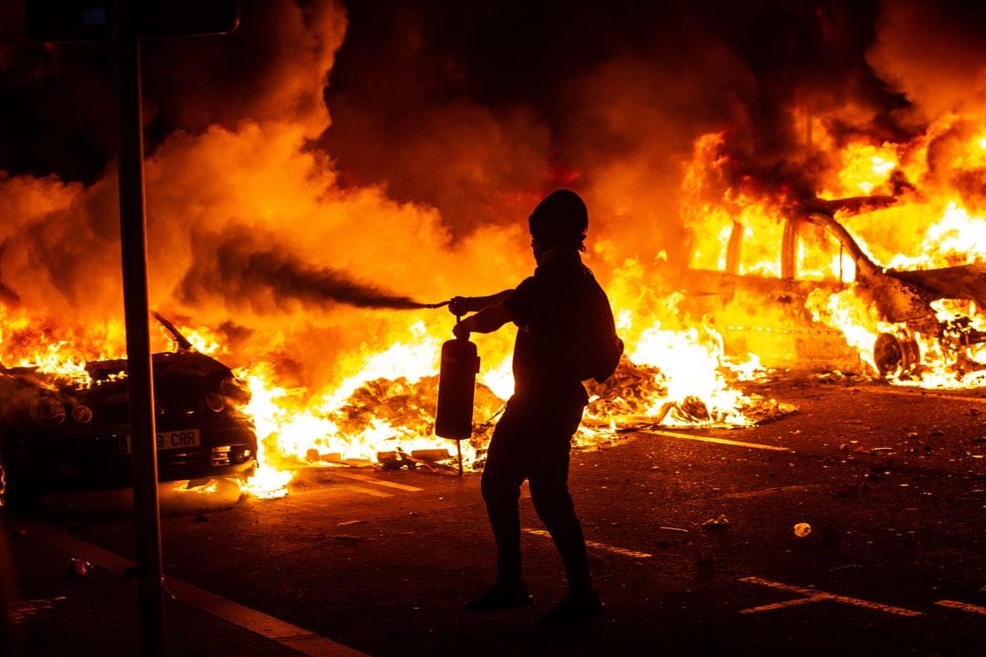 Una persona trata de apagar el fuego de las hogueras, en una protesta de los CDR en Barcelona, en 2021. Archivo.