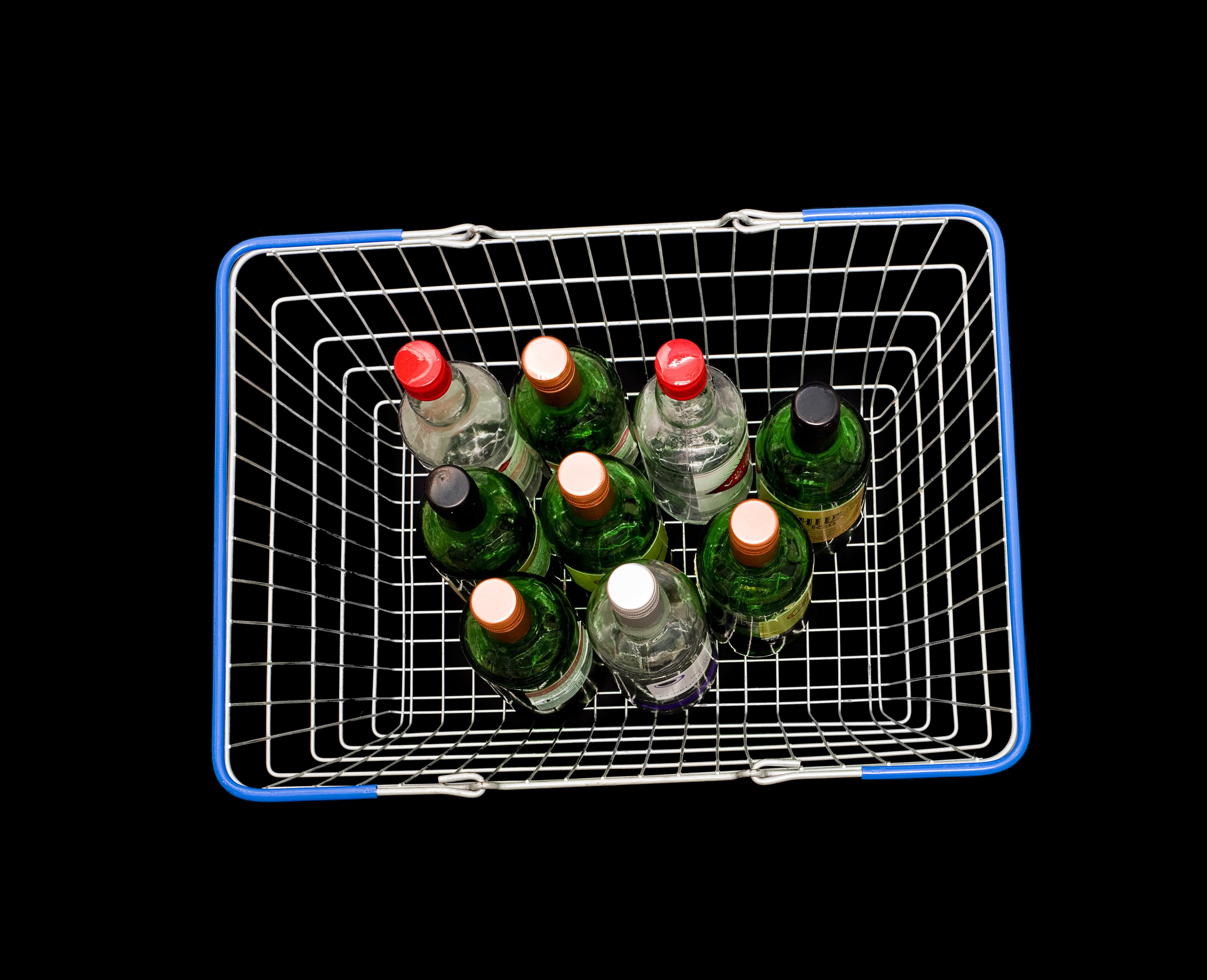 Wine bottles in shopping basket on black