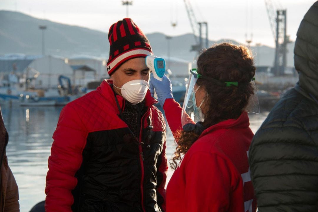 Voluntaria de Cruz Roja atiende a uno de los inmigrantes trasladados al puerto de Motril