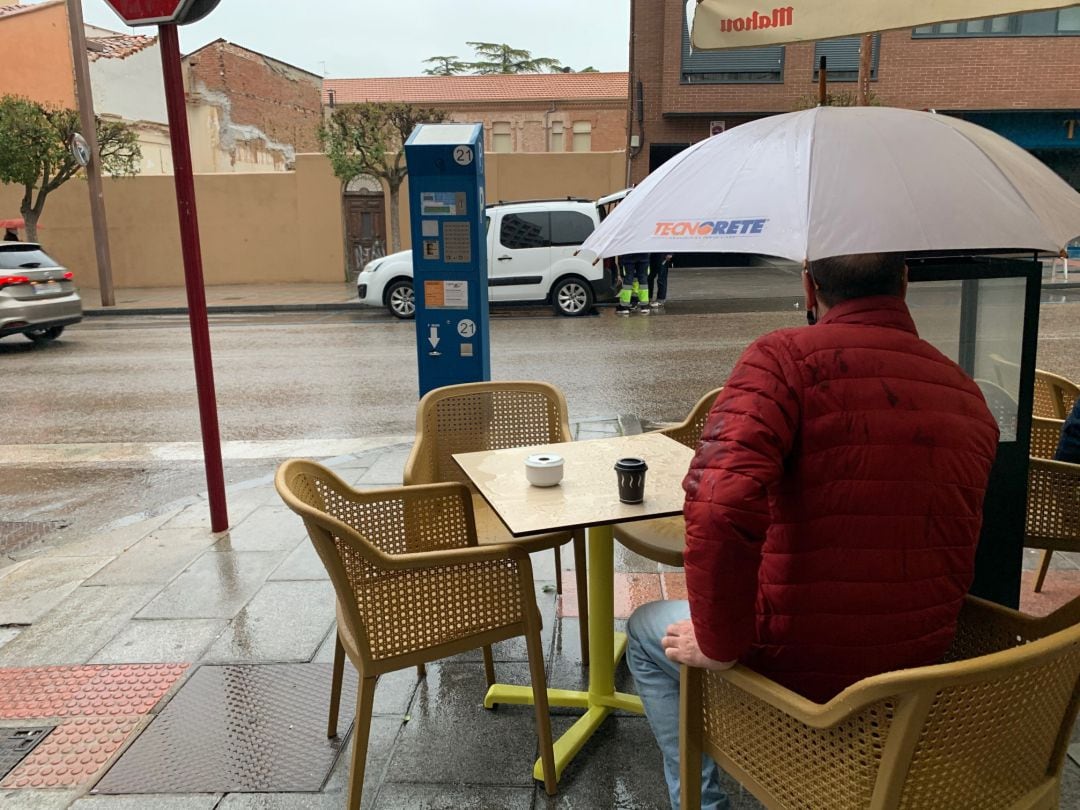 Un cliente tomando café bajo la lluvia hoy en Guadalajara