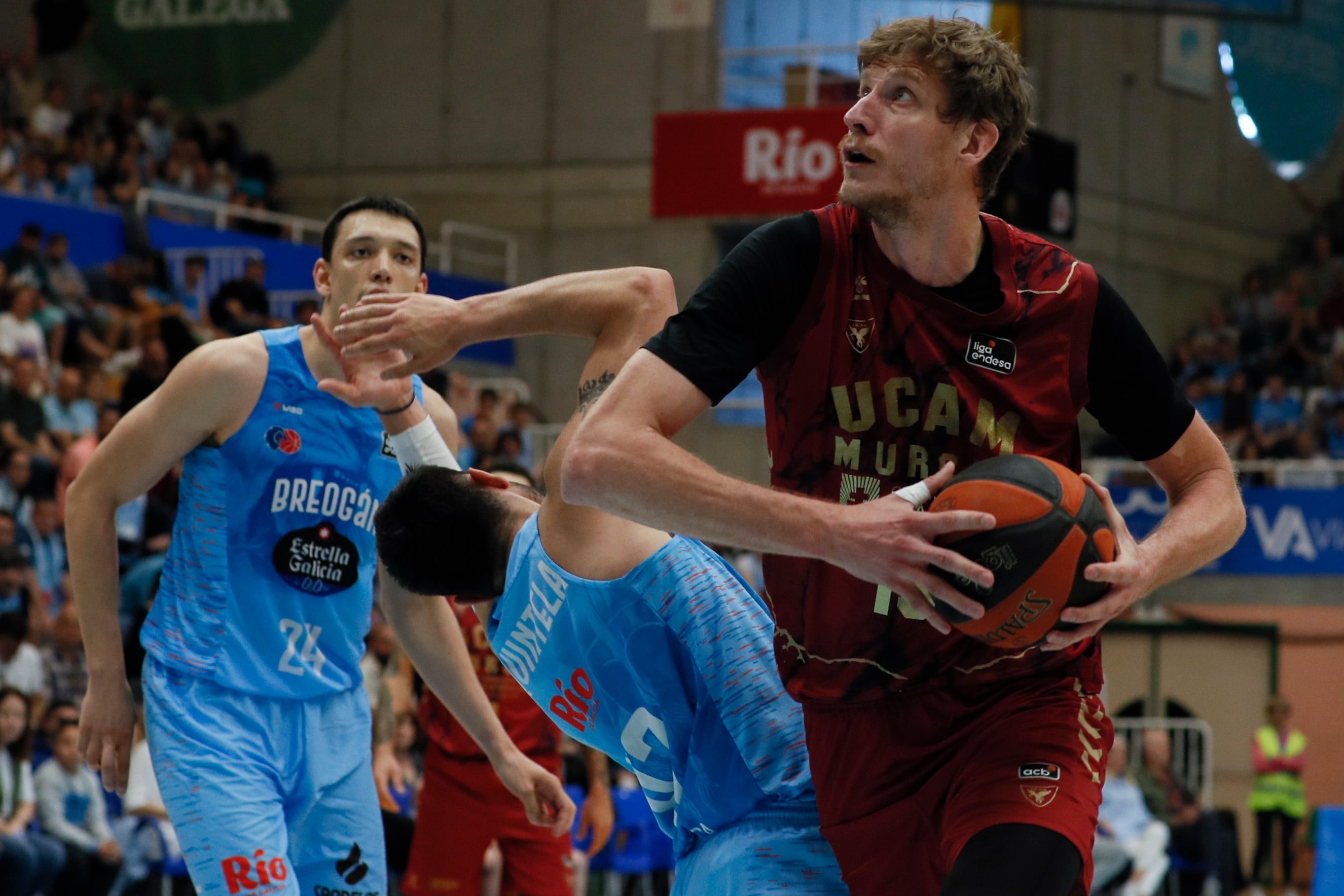 LUGO (GALICIA), 07/05/2023.- El pívot ucraniano del UCAM Murcia Artem Pustovyi (d) entra a canasta ante los jugadores del Breogan Nikola Tanaskovic (i) y Eric Quintela (c), durante el partido correspondiente a la jornada 31 de la Liga Endesa que enfrenta este domingo al Breogán y al UCAM Murcia en el Pazo dos Deportes de Lugo. EFE/ Pedro Eliseo Agrelo Trigo
