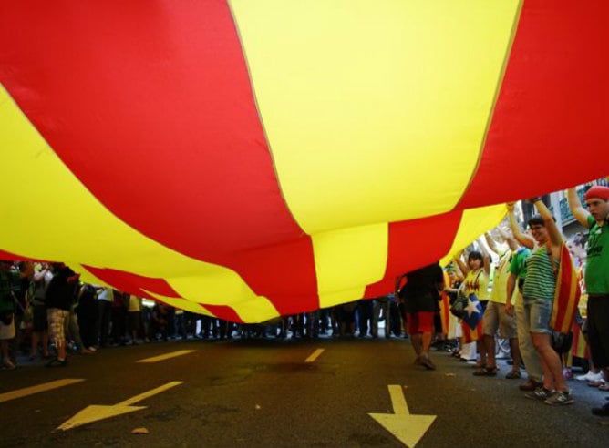 Varias decenas de catalanes ondean una bandera gigante de Cataluña