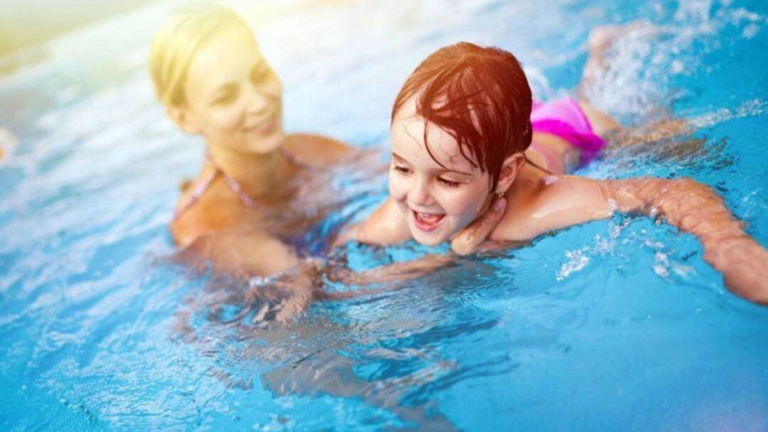 Una menor con su madre en una piscina 