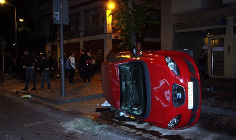 Un cotxe bolcat a Travessera de Gràcia, davant el Banc Expropiat, després d&#039;una manifestació en protesta del seu desallotjament