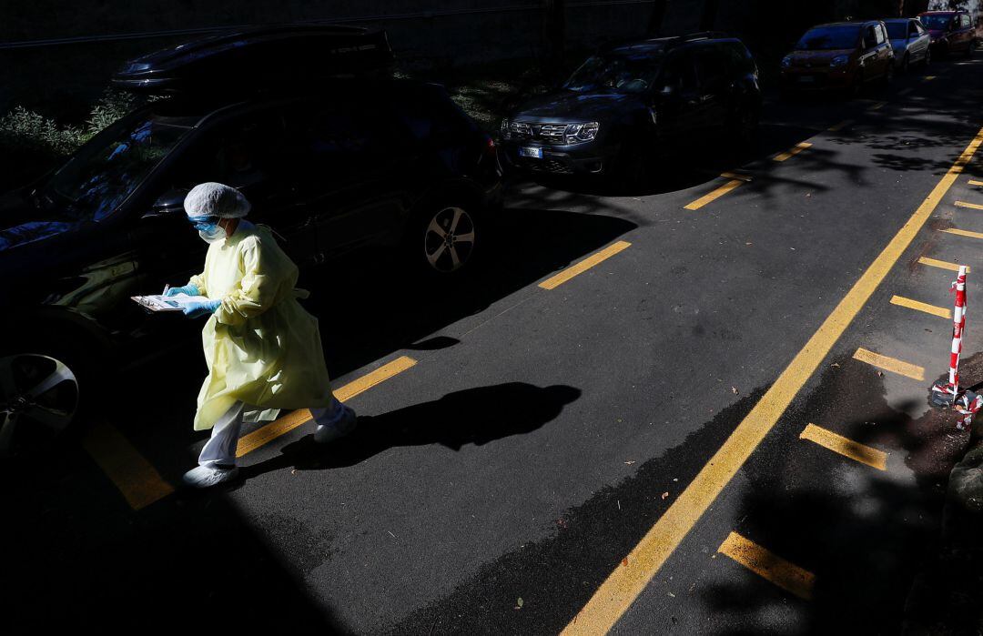 Personal sanitario se mueve entre varios coches en un centro de realización de pruebas PCR. Imagen de archivo