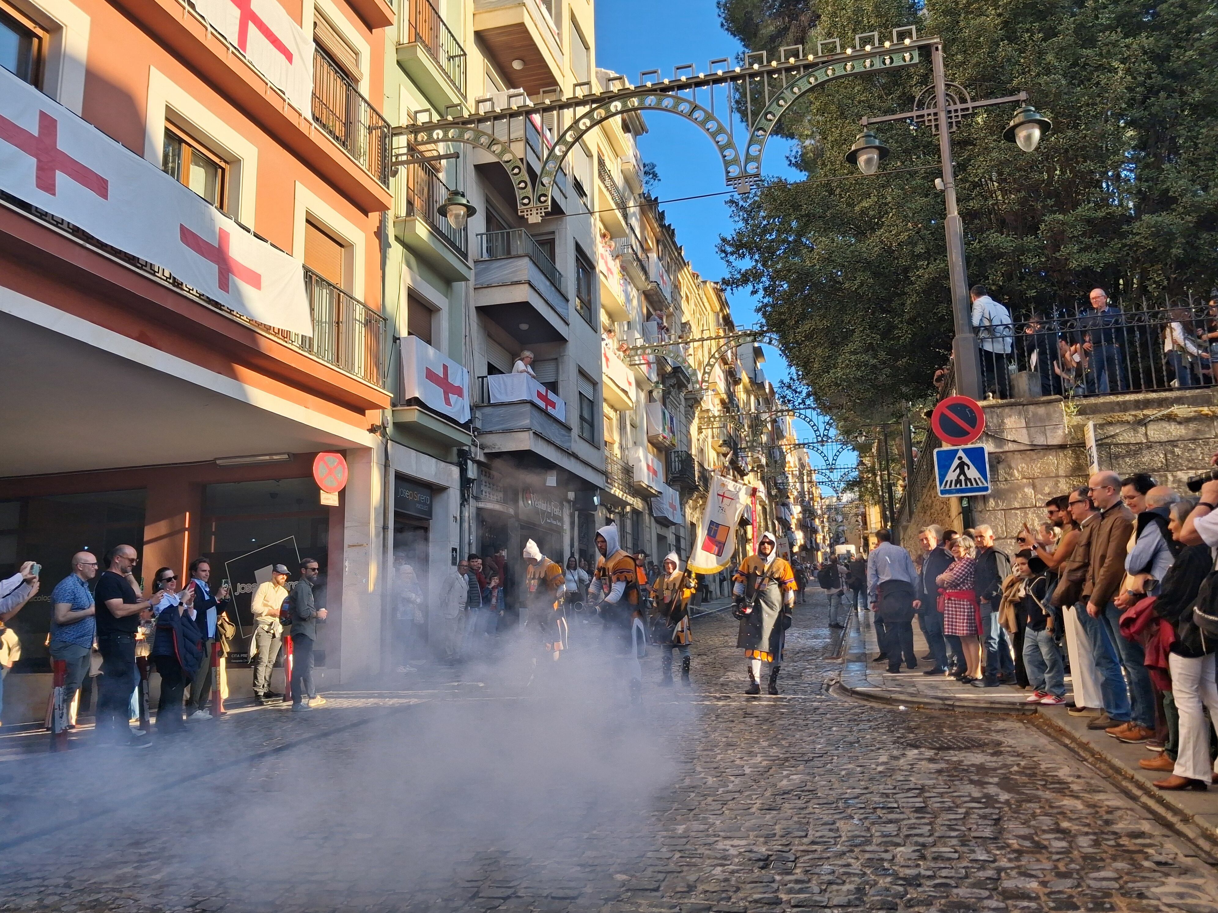 Los festeros de la Filà Asturianos de Alcoy disparando el arcabuz por la calle Sant Nicolau.