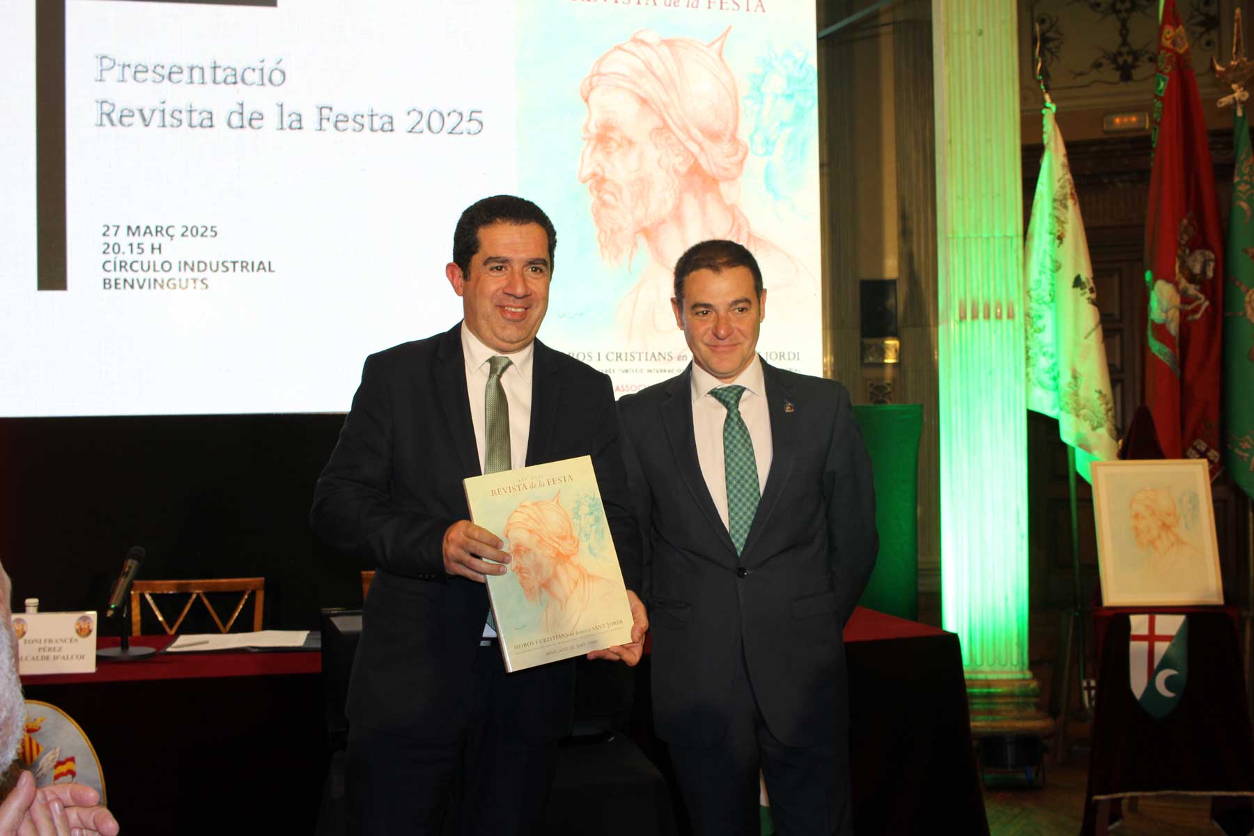 El alcalde Toni Francés sostiene el primer ejemplar de la Revista de Fiestas 2025 tras serle entregado por el presidente de la Asociación de San Jorge, Paco García