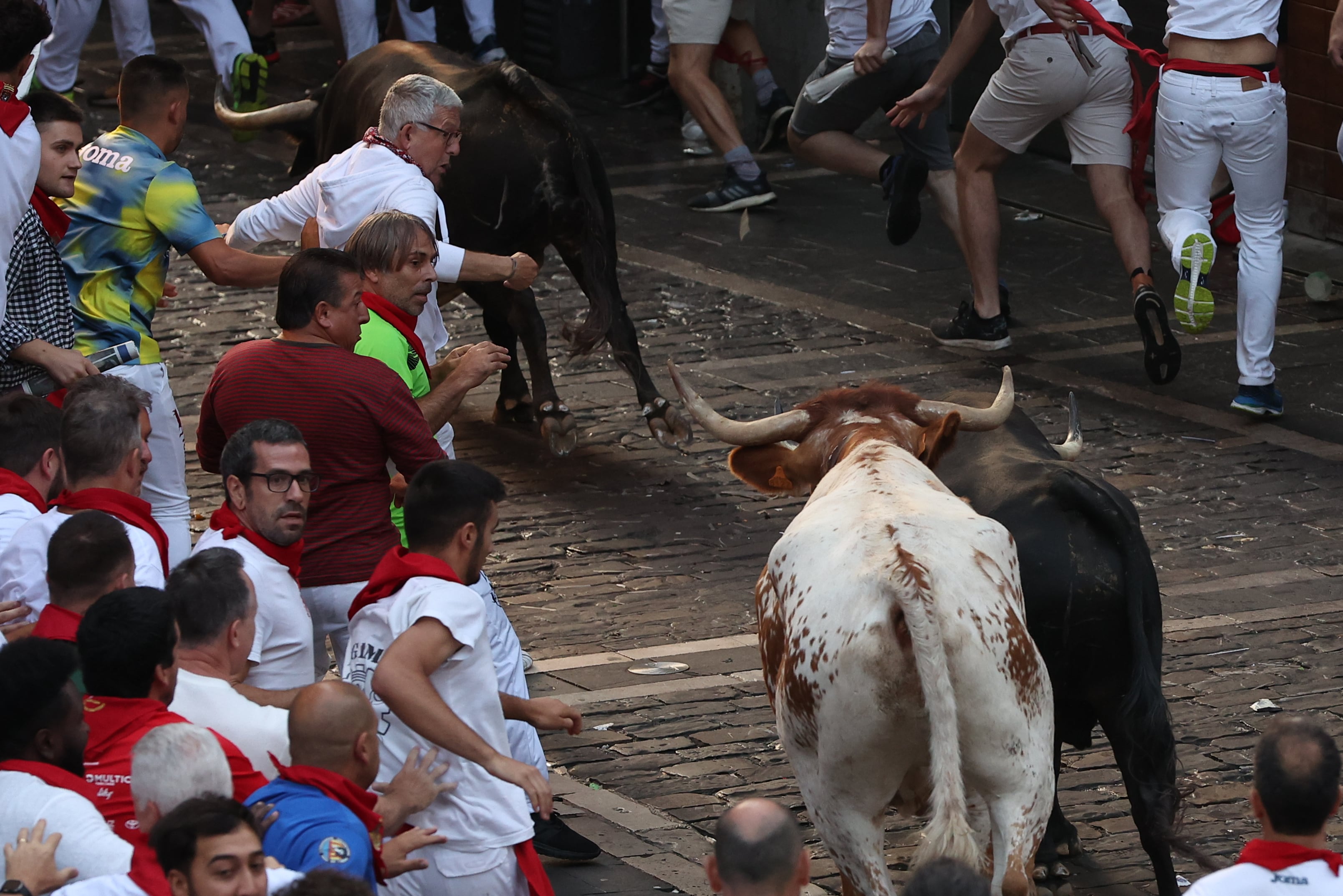 Mozos son perseguidos por toros de la ganadería de Cebada Gago en el tramo final que va de la Cuesta de Santo Domingo a la curva de Mercaderes durante el tercer encierro de los sanfermines 2023