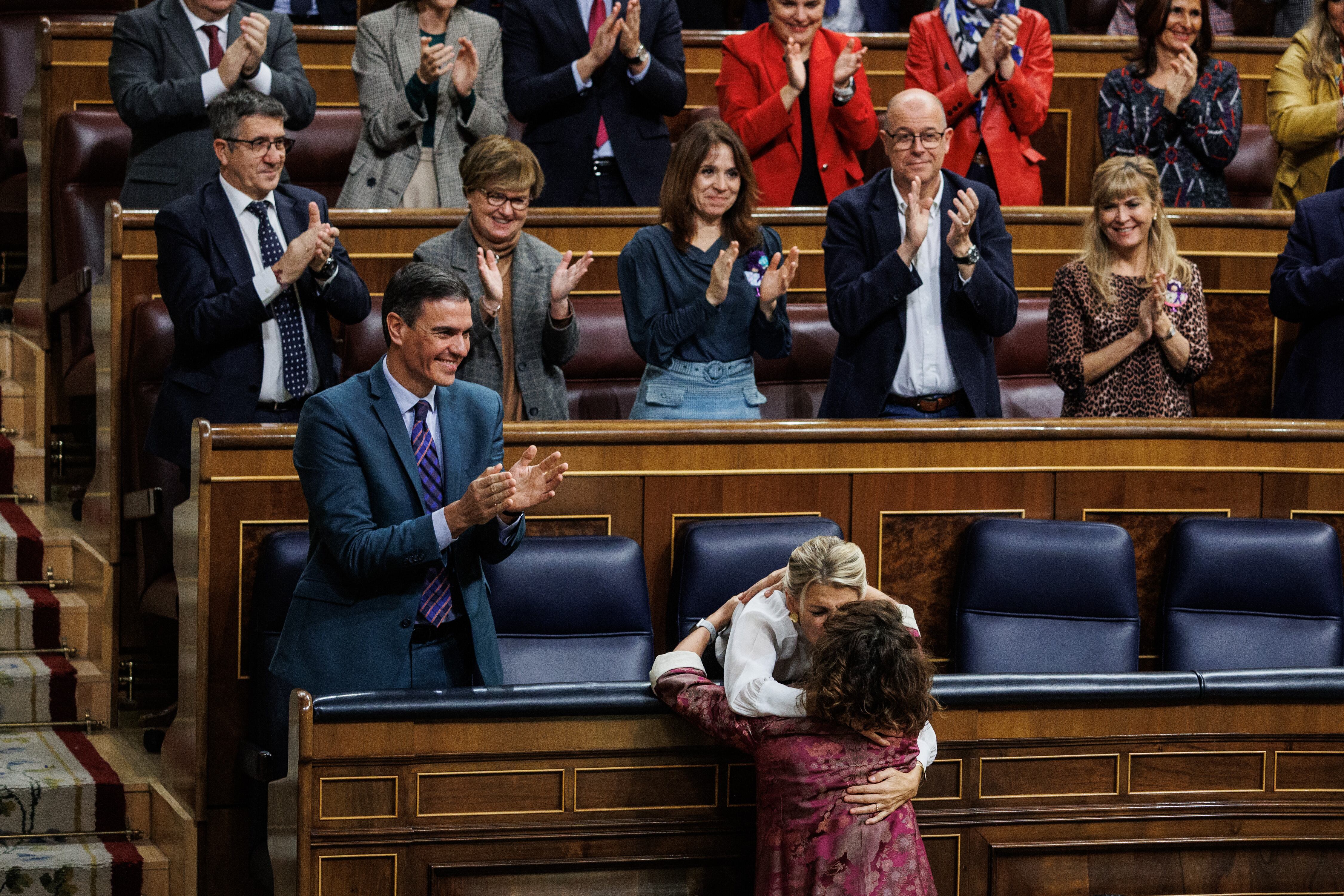 La vicepresidenta segunda del Gobierno, Yolanda Díaz, se abraza a la ministra de Hacienda, María Jesús Montero, tras aprobar los Presupuestos en el Congreso. A la izquierda, el presidente, Pedro Sánchez, aplaude y tras él, toda la bancada socialista.