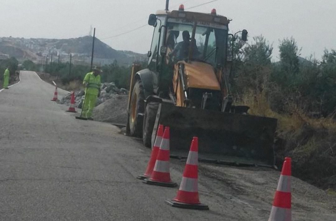 Una grúa y varios operarios arreglando los baches de la carretera de Vilches.