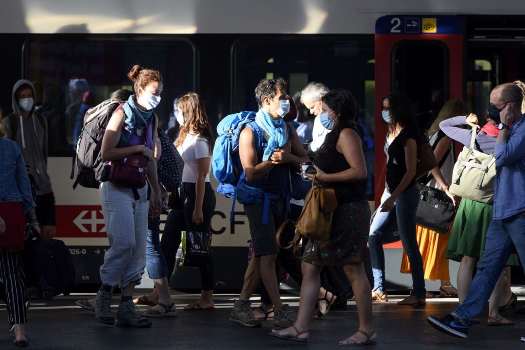 Varios pasajeros de un tren llevan mascarilla en la estación de Lausanne, en Suiza