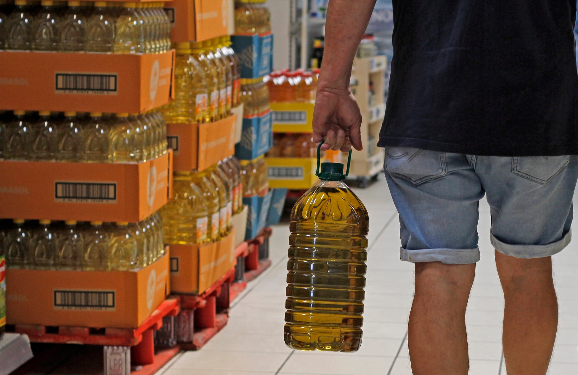 Un hombre carga con una garrafa de aceite de oliva en un supermercado