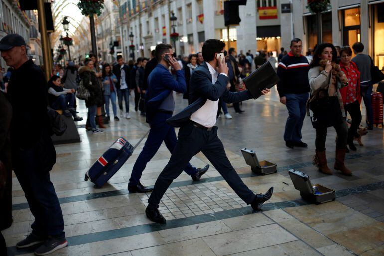 Street performers dressed up as businessmen perform as they ask for alms at Marques de Larios street in downtown Malaga, southern Spain January 3, 2018