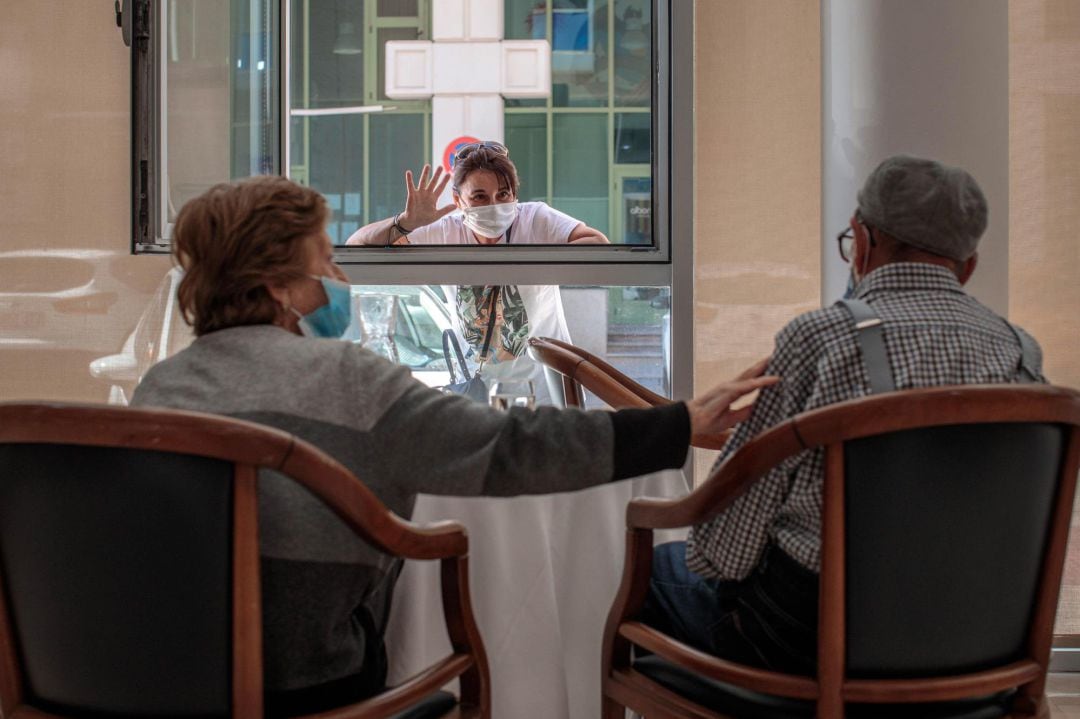 Una persona conversa con sus padres a través de una ventana habilitada en la residencia de mayores Ballesol Patacona, en Valencia, para que los residentes puedan recibir visitas de sus familiares