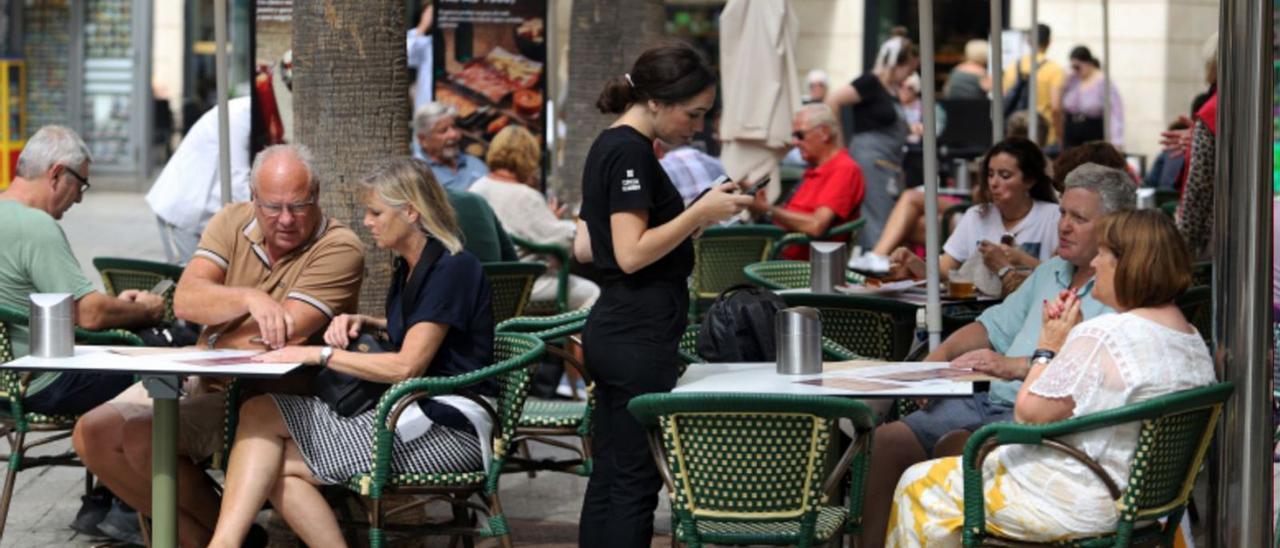 Una trabajadora del sector de la hostelería atiende a unos clientes.