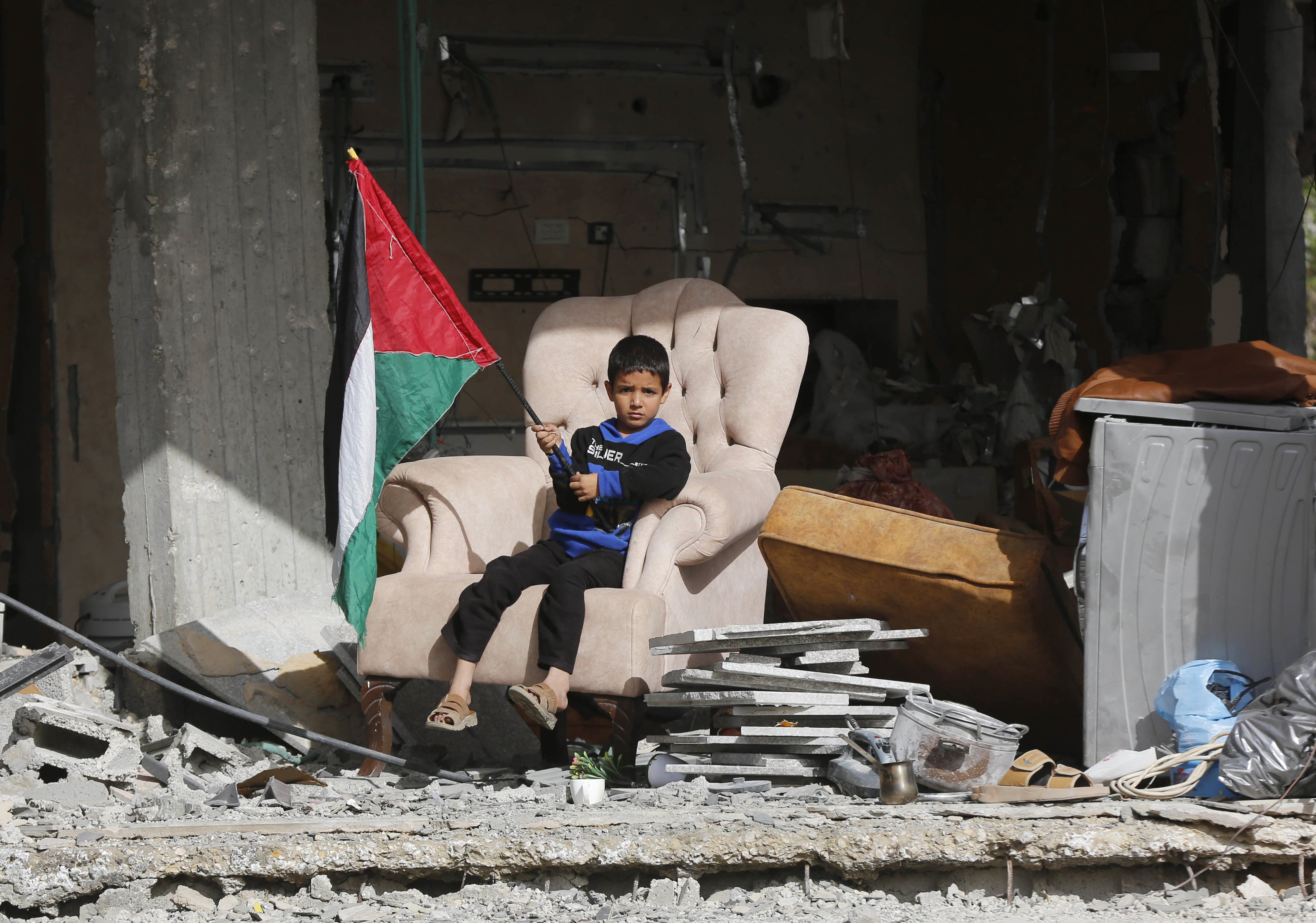 Un niño sostiene una bandera palestina sobre los escombros de una zona residencial de la localidad gazatí de Jan Yunis atacada por Israel