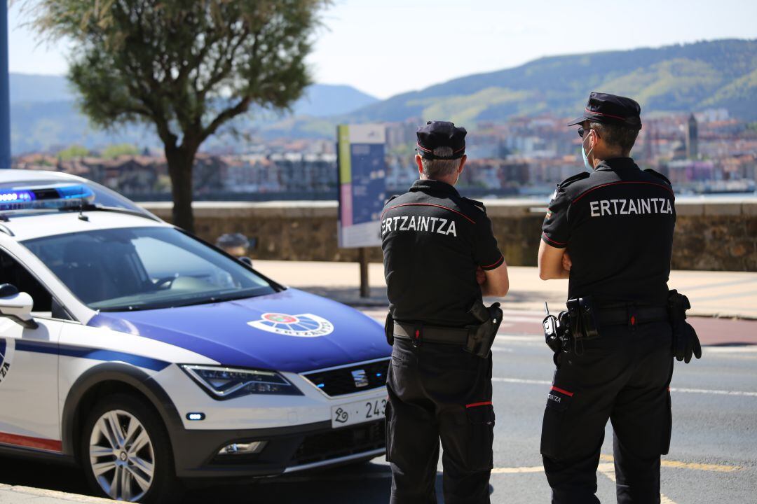 Dos agentes de la Ertzaintza junto a un coche patrulla, en una imagen de archivo