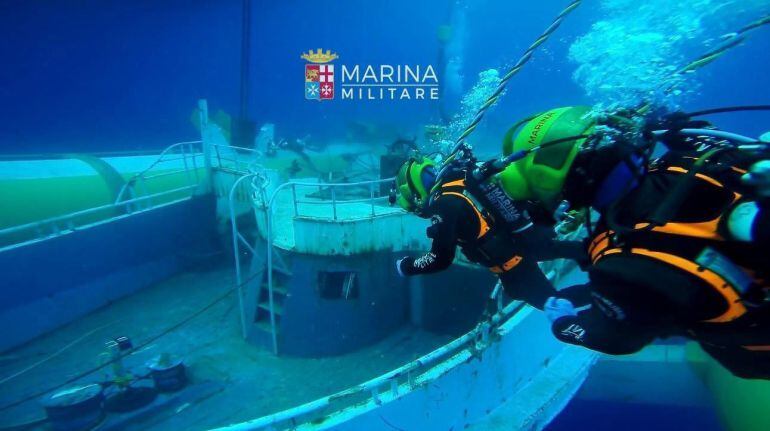 Buzos de la marina italiana exploran una barcaza en el fondo del mar. Se hundió en 2015 con unos 700 inmigrantes a bordo.