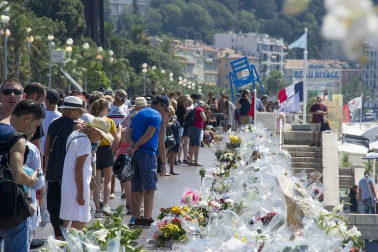 Multitud de personas se detienen ante las flores y velas depositadas en el paseo de los Ingleses (Niza).