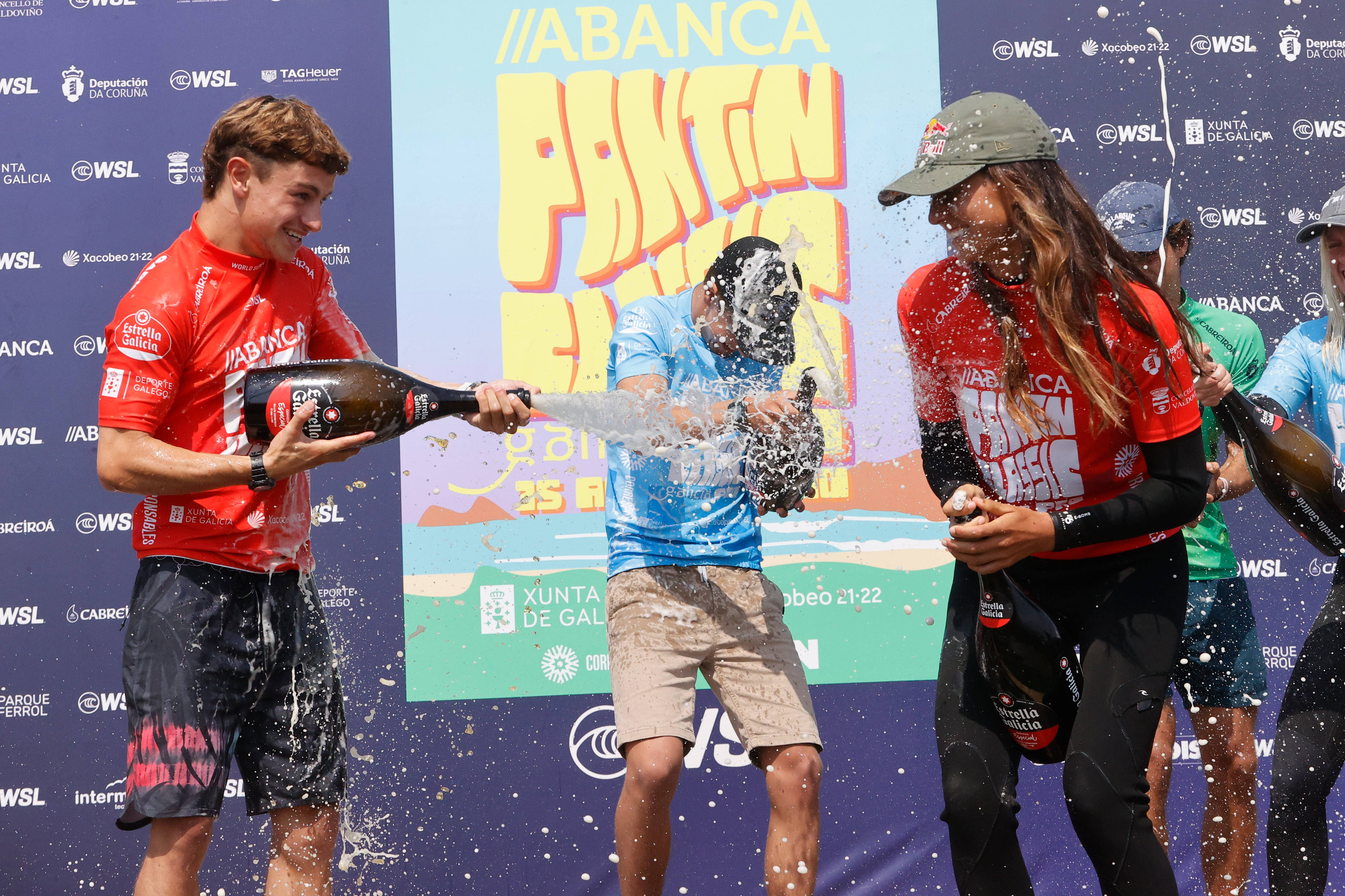 VALDOVIÑO, 17/07/2022.- La surfista portuguesa Teresa Bonvalot y el vasco Adur Amatriain (i) celebran en el podio este domingo su victoria en la final del Abanca Pantin Classic Galicia Pro en Valdoviño. EFE/ Kiko Delgado