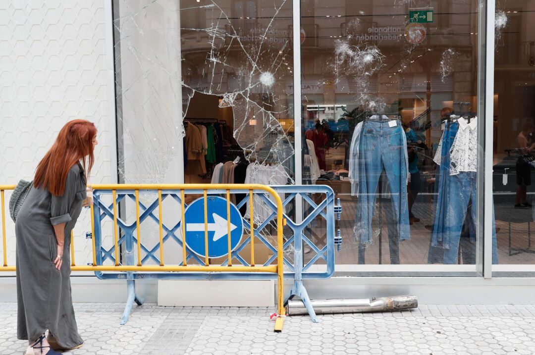 Una mujer observa un escaparate atacado el domingo en el centro de San Sebastián