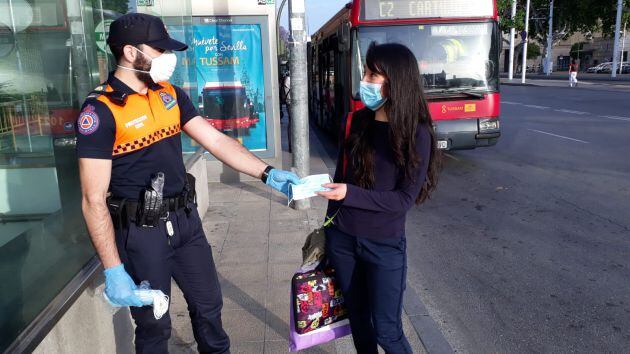 Voluntario de Protección Civil repartiendo mascarillas en Sevilla