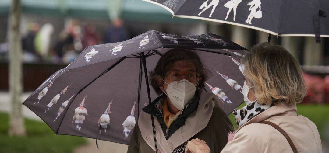 Dos mujeres conversan en la calle protegidas por sus mascarillas.