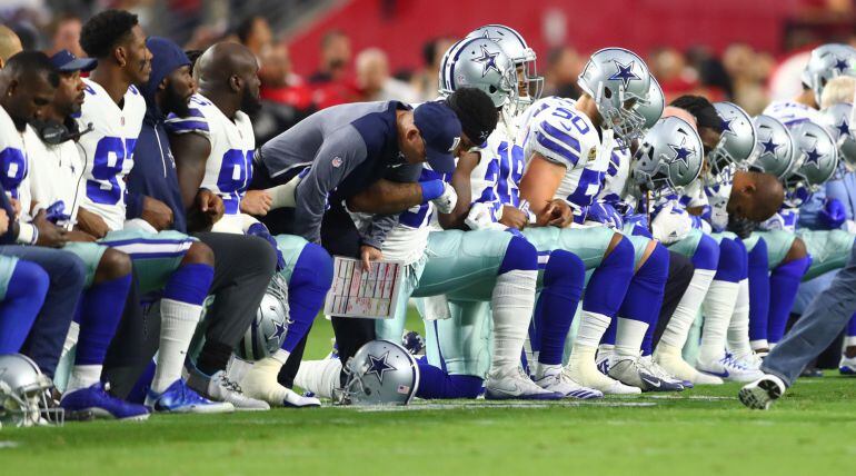 Los jugadores de los Dallas Cowboys hincan la rodilla mientras suena el himno de Estados Unidos.