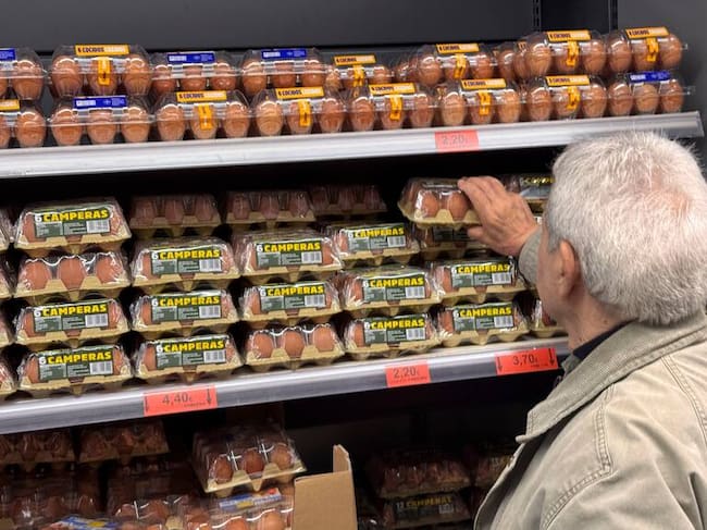 Un hombre coge unos huevos camperos en un supermercado