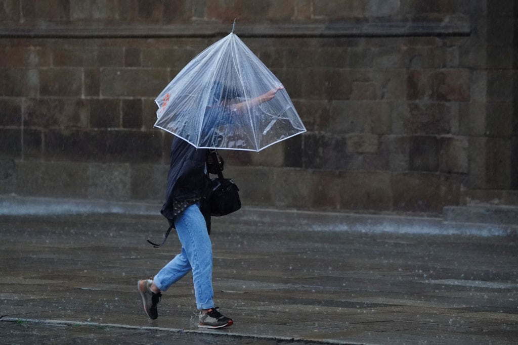 Una persona se protege de la lluvia y el viento bajo un paraguas